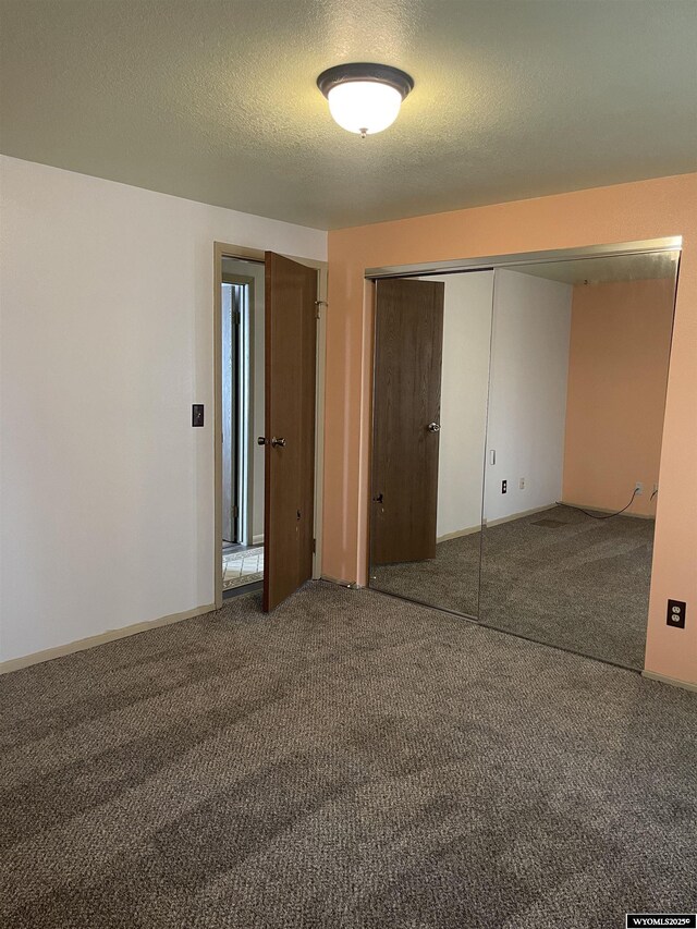 unfurnished bedroom featuring a closet, carpet floors, and a textured ceiling