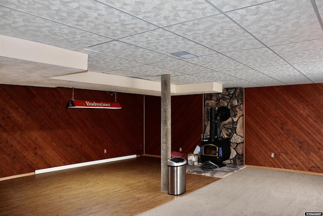 basement with a wood stove and wooden walls