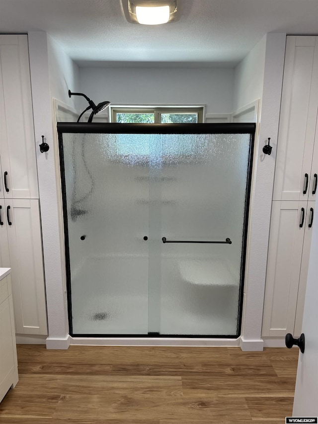 bathroom featuring a shower with shower door and hardwood / wood-style flooring