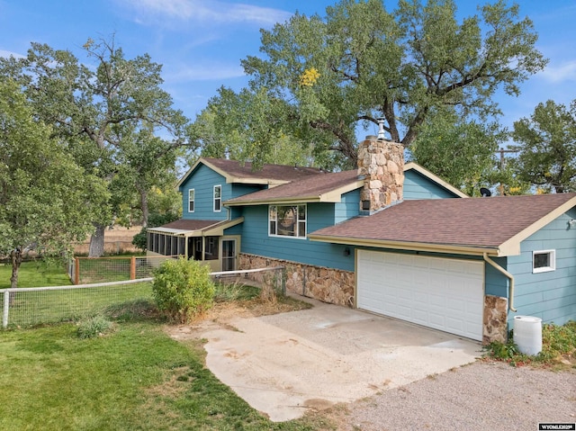 tri-level home featuring an attached garage, a sunroom, concrete driveway, stone siding, and a front yard