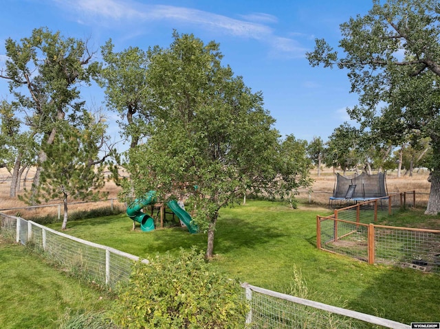 view of yard with a trampoline, fence, a playground, and a rural view