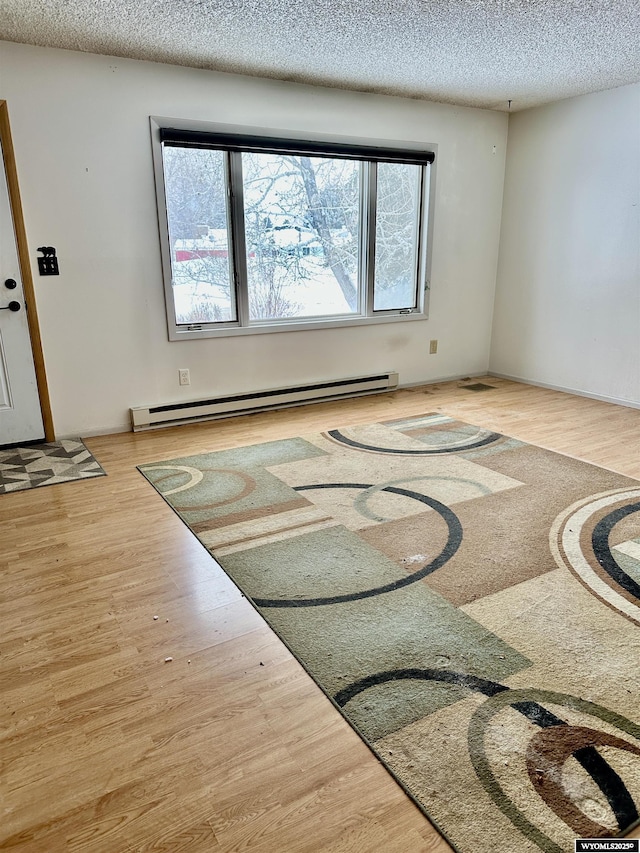 spare room featuring a textured ceiling, light hardwood / wood-style flooring, and baseboard heating