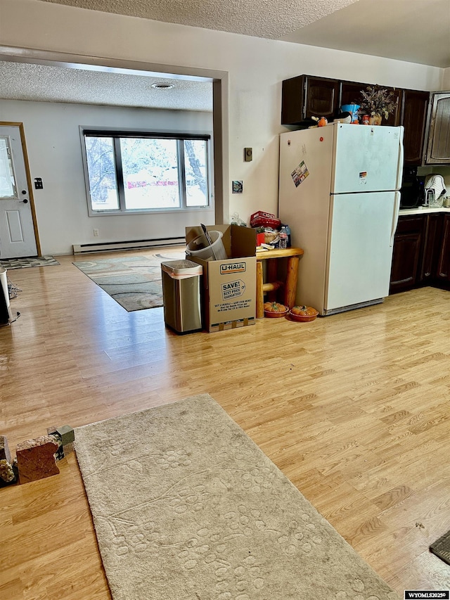 kitchen featuring white fridge, dark brown cabinetry, baseboard heating, and light hardwood / wood-style flooring