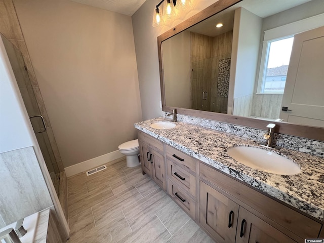 bathroom featuring vanity, toilet, and a shower with shower door