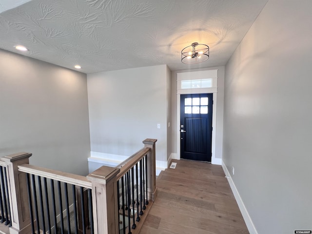 doorway featuring a chandelier, wood-type flooring, and a textured ceiling