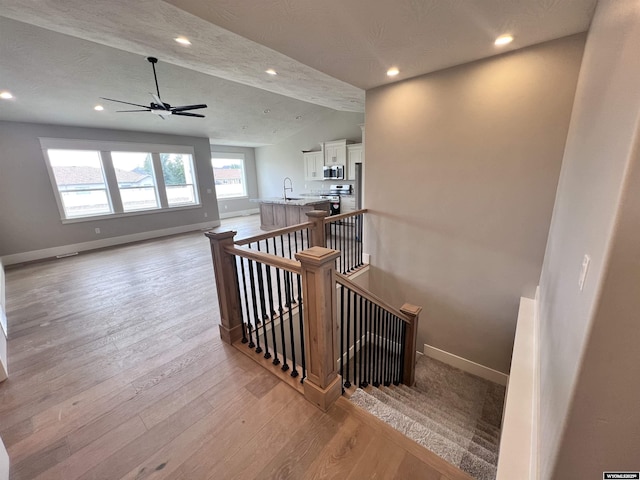 staircase featuring sink, hardwood / wood-style flooring, vaulted ceiling with beams, ceiling fan, and a textured ceiling