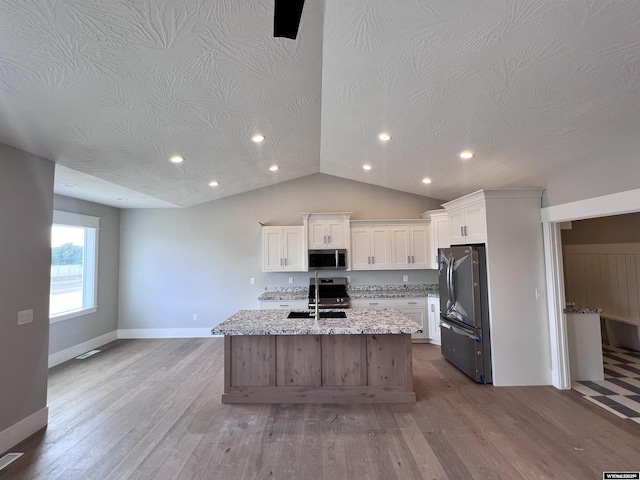 kitchen featuring sink, light stone counters, light hardwood / wood-style flooring, white cabinets, and appliances with stainless steel finishes