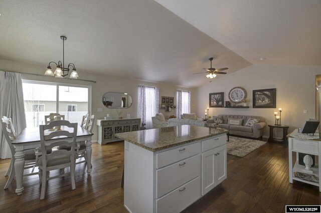 kitchen with white cabinetry, a center island, hanging light fixtures, vaulted ceiling, and ceiling fan with notable chandelier