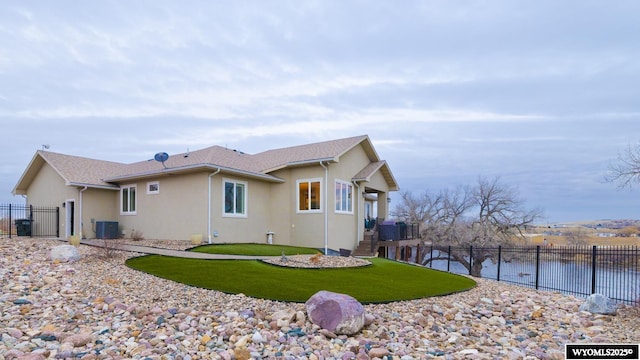 back of property featuring a yard, a water view, and central AC