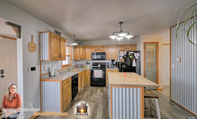 kitchen with black appliances, decorative light fixtures, light hardwood / wood-style flooring, an inviting chandelier, and a kitchen island