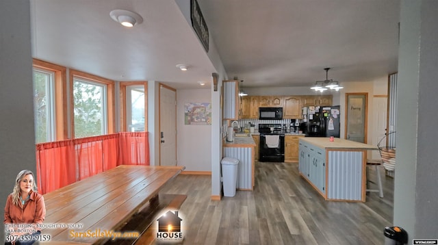 kitchen featuring a notable chandelier, decorative light fixtures, decorative backsplash, a kitchen island, and black appliances