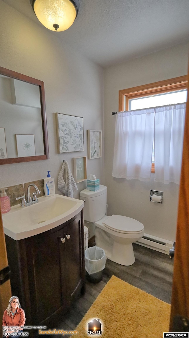 bathroom with toilet, vanity, a baseboard radiator, and hardwood / wood-style flooring