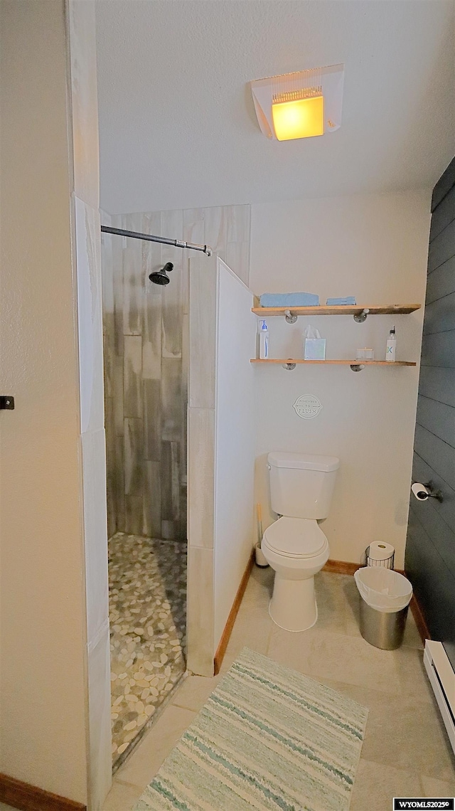 bathroom featuring toilet, a tile shower, and a baseboard heating unit