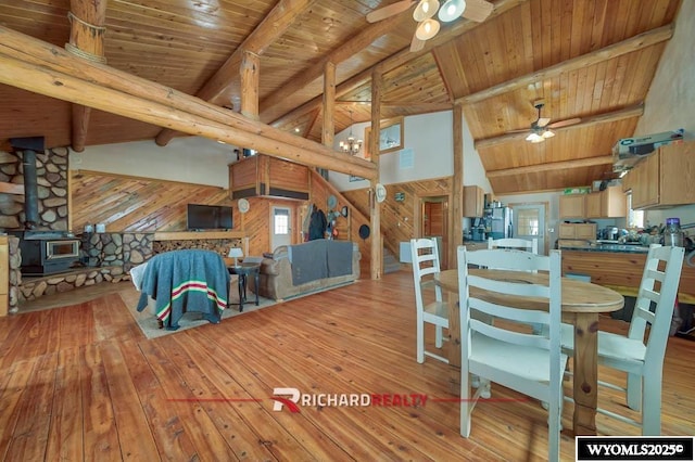 dining room featuring beam ceiling, a wood stove, and wood ceiling