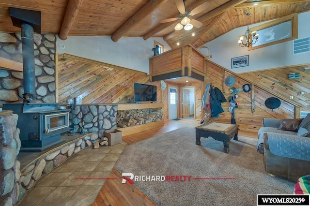 living room featuring beam ceiling, ceiling fan with notable chandelier, wood walls, and wood ceiling