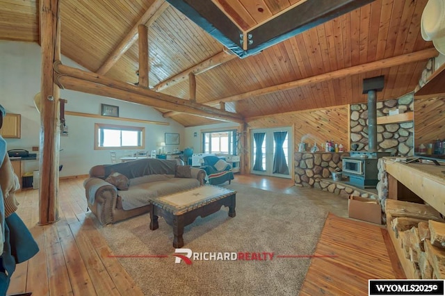 living room with a wood stove, beamed ceiling, wooden walls, wood ceiling, and hardwood / wood-style flooring