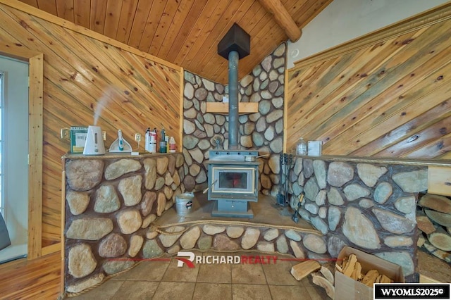 unfurnished living room featuring tile patterned floors, wood ceiling, lofted ceiling with beams, a wood stove, and wood walls