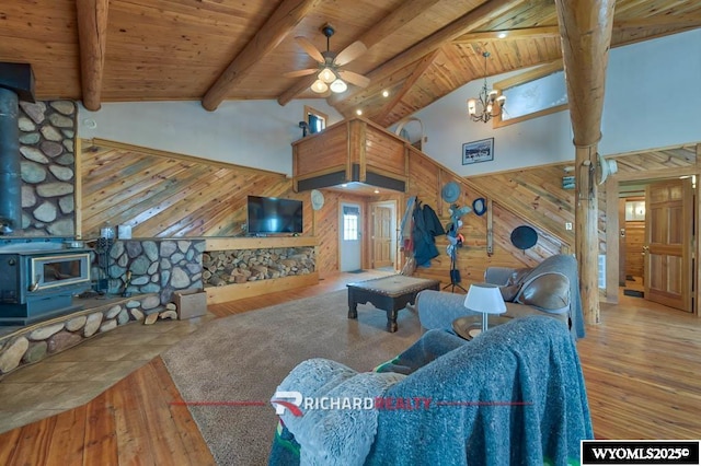 living room with beam ceiling, wooden ceiling, a wood stove, and wooden walls