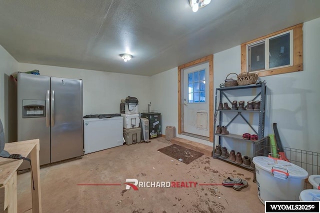 interior space featuring refrigerator, concrete flooring, and stainless steel refrigerator with ice dispenser