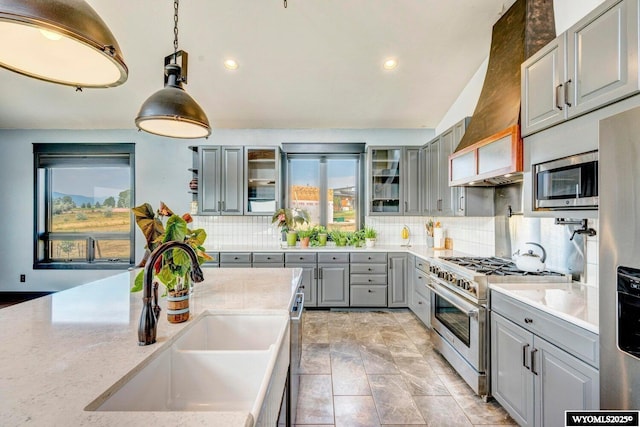 kitchen with premium range hood, gray cabinetry, stainless steel appliances, sink, and pendant lighting