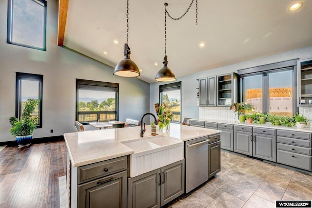 kitchen featuring light stone countertops, sink, dishwasher, vaulted ceiling with beams, and a kitchen island with sink