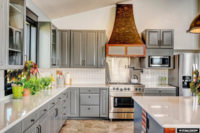 kitchen with decorative backsplash, light stone countertops, premium range hood, and stainless steel appliances