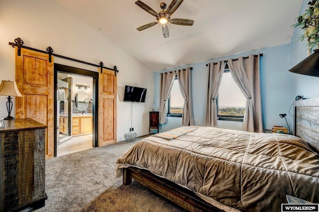 carpeted bedroom with ensuite bathroom, ceiling fan, a barn door, and lofted ceiling