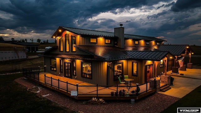 back house at dusk featuring a wooden deck