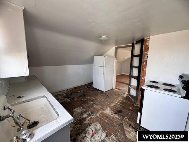 kitchen featuring vaulted ceiling, sink, and white appliances