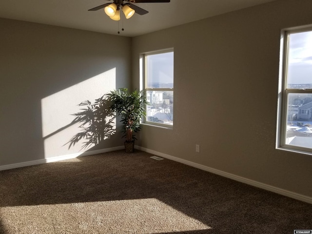 carpeted spare room featuring ceiling fan and a healthy amount of sunlight