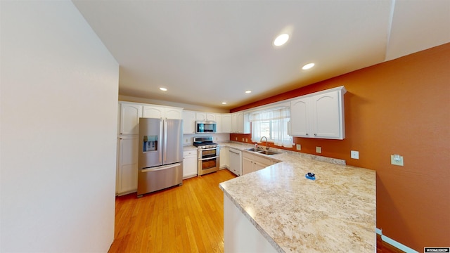 kitchen featuring sink, stainless steel appliances, light hardwood / wood-style flooring, kitchen peninsula, and white cabinets