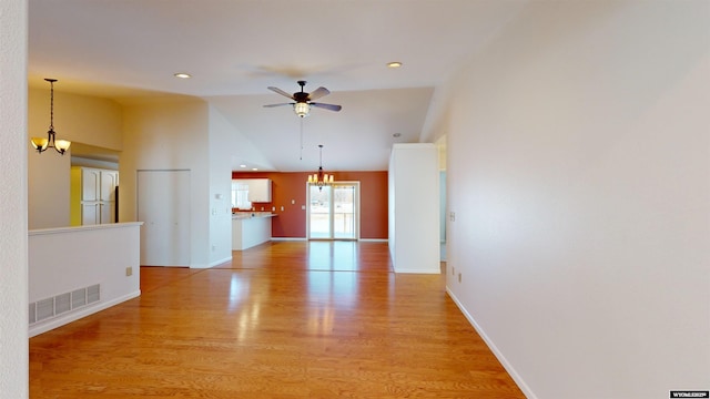 interior space featuring ceiling fan with notable chandelier, light hardwood / wood-style flooring, and vaulted ceiling