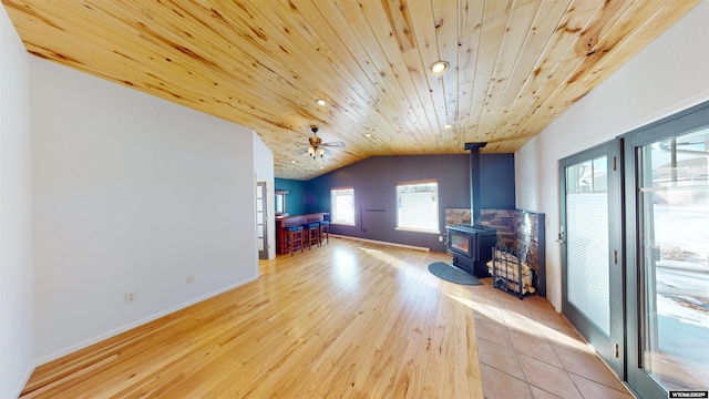 unfurnished living room featuring vaulted ceiling, ceiling fan, light hardwood / wood-style flooring, wooden ceiling, and a wood stove