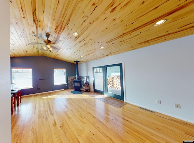 additional living space with a wood stove, wooden ceiling, lofted ceiling, and light hardwood / wood-style floors