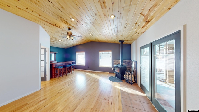 bonus room with lofted ceiling, a wood stove, light hardwood / wood-style flooring, ceiling fan, and wood ceiling