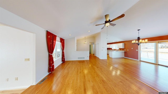 unfurnished living room featuring lofted ceiling, hardwood / wood-style floors, and ceiling fan with notable chandelier