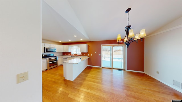 kitchen with white cabinetry, sink, stainless steel appliances, an inviting chandelier, and kitchen peninsula