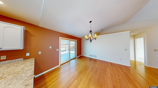 unfurnished dining area featuring light hardwood / wood-style flooring, lofted ceiling, and an inviting chandelier