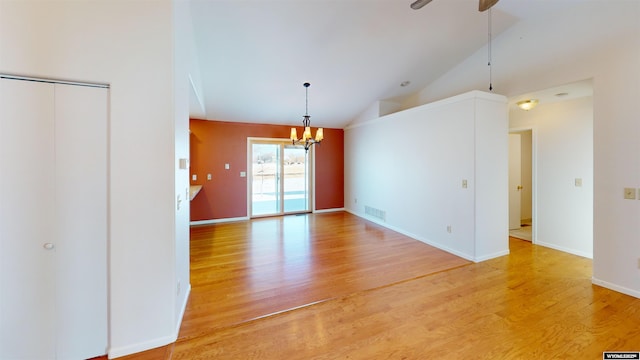 unfurnished room with ceiling fan with notable chandelier, wood-type flooring, and lofted ceiling