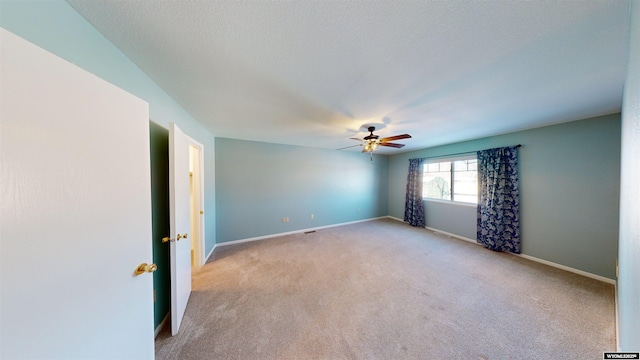 carpeted empty room with ceiling fan and a textured ceiling