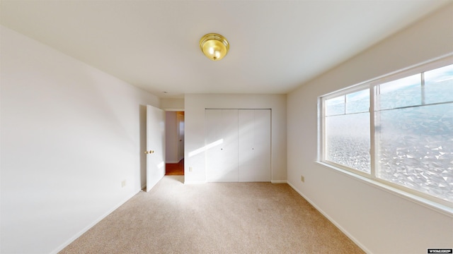 unfurnished bedroom with light carpet and a closet