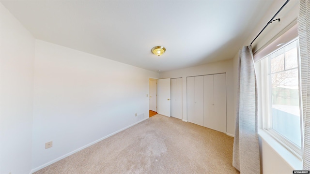 unfurnished bedroom with light carpet and two closets