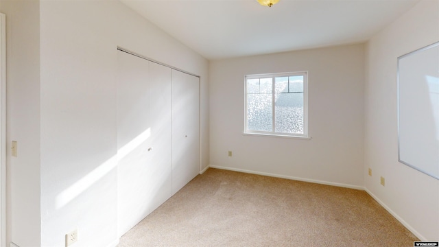 unfurnished bedroom with light carpet and a closet