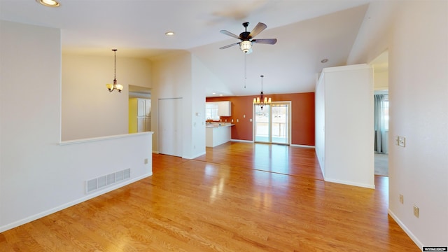 unfurnished living room featuring ceiling fan with notable chandelier, light hardwood / wood-style floors, and vaulted ceiling