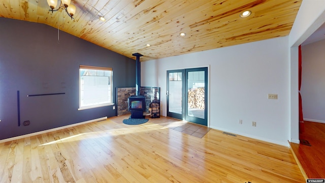 unfurnished room featuring a wood stove, wooden ceiling, an inviting chandelier, light hardwood / wood-style flooring, and vaulted ceiling