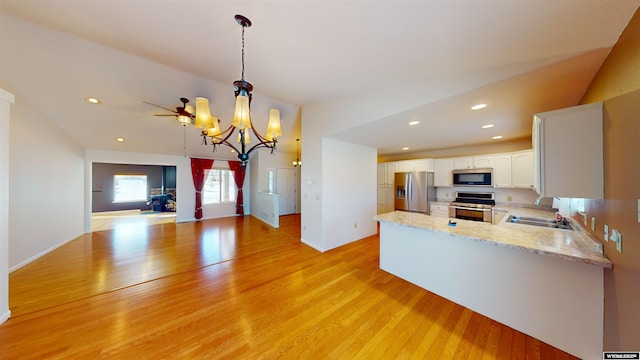 kitchen with white cabinets, decorative light fixtures, light hardwood / wood-style floors, kitchen peninsula, and stainless steel appliances