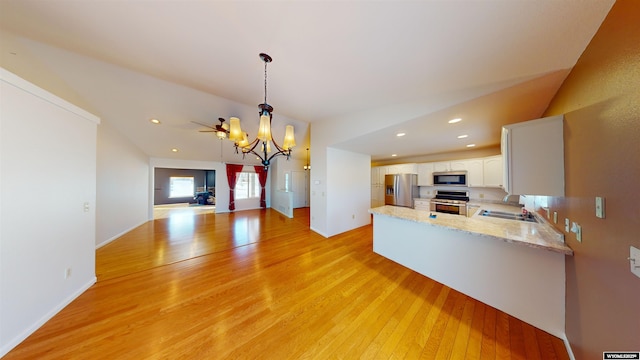 kitchen featuring white cabinetry, stainless steel appliances, kitchen peninsula, pendant lighting, and light wood-type flooring