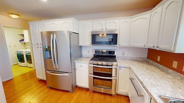 kitchen with light stone countertops, light wood-type flooring, white cabinetry, and appliances with stainless steel finishes