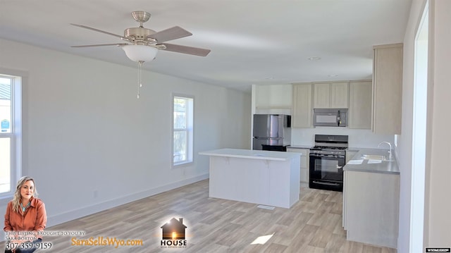 kitchen with plenty of natural light, black appliances, light wood-type flooring, and sink