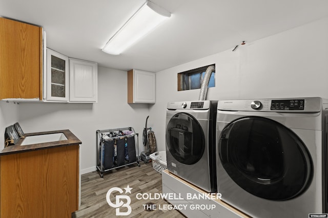 washroom featuring cabinets, independent washer and dryer, and light hardwood / wood-style flooring